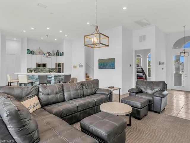 Living room with a high ceiling, light tile patterned floors, and an inviting chandelier