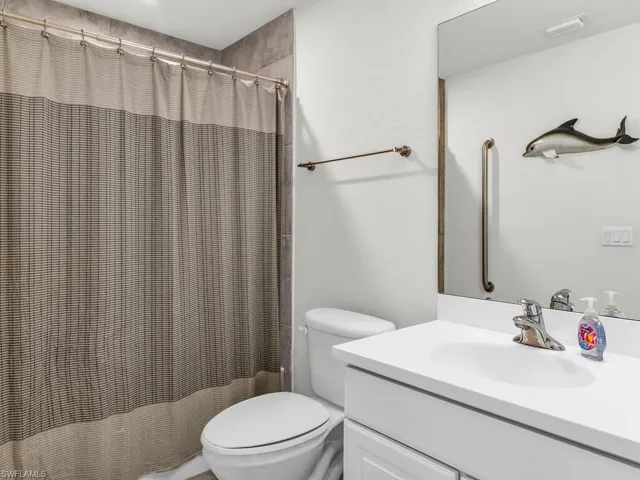 Bathroom with vanity, a shower with shower curtain, and toilet