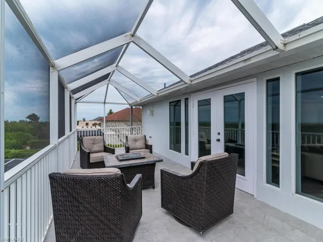 View of patio featuring an outdoor living space with a fire pit and glass enclosure