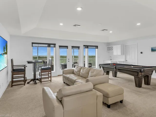 Game room featuring french doors, a raised ceiling, indoor bar, and light colored carpet