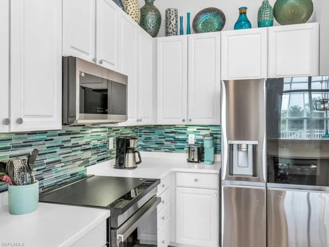 Kitchen with white cabinetry, appliances with stainless steel finishes, and decorative backsplash