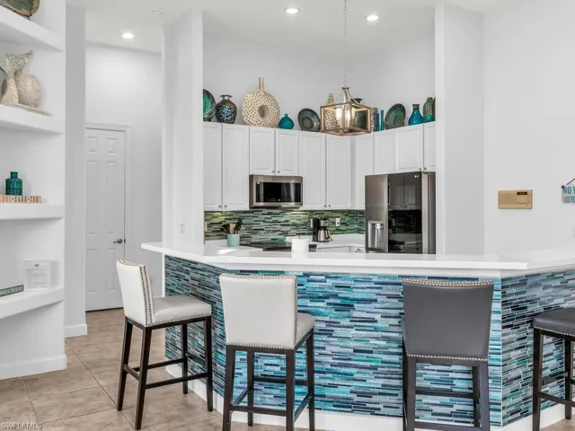 Kitchen featuring white cabinetry, kitchen peninsula, appliances with stainless steel finishes, and a kitchen bar