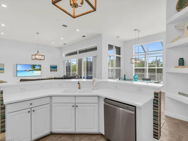 Kitchen with white cabinets, light tile patterned floors, dishwasher, a notable chandelier, and sink