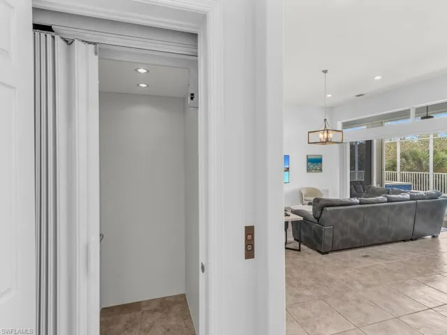 Corridor with an inviting chandelier, elevator, and light tile patterned floors