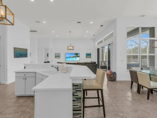 Kitchen featuring sink, light tile patterned flooring, a notable chandelier, pendant lighting, and white cabinets