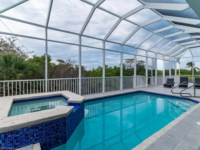 View of swimming pool featuring an in ground hot tub, a patio, and a lanai