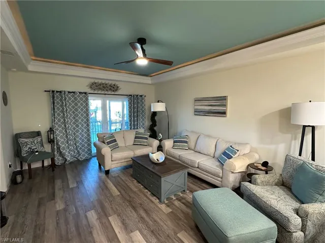 Living room featuring a ceiling fan, a raised ceiling, ornamental molding, and french doors