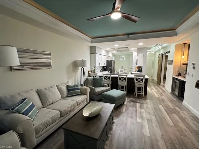 Living area with a barn door, ornamental molding, ceiling fan, and a tray ceiling