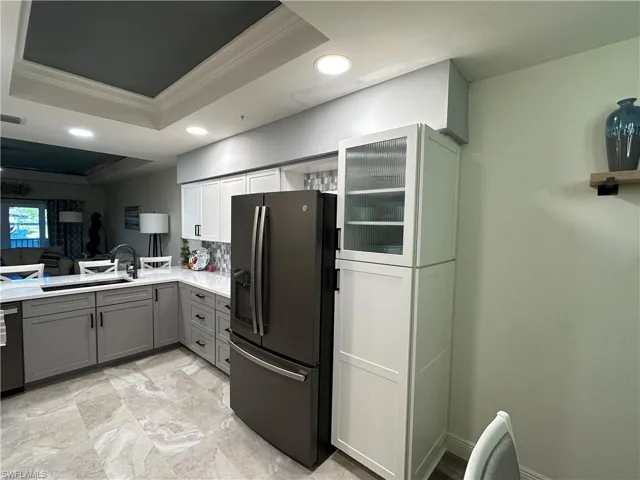 Kitchen with gray cabinets, recessed lighting, a tray ceiling, black fridge, and ornamental molding
