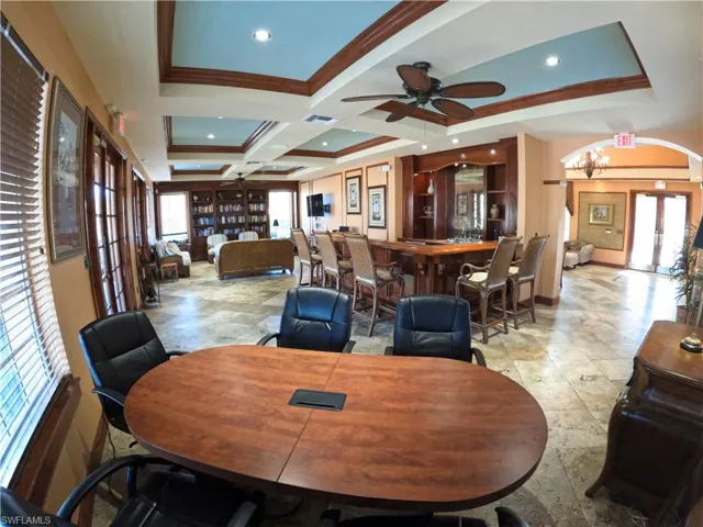 Dining space featuring french doors, a raised ceiling, crown molding, arched walkways, and a ceiling fan