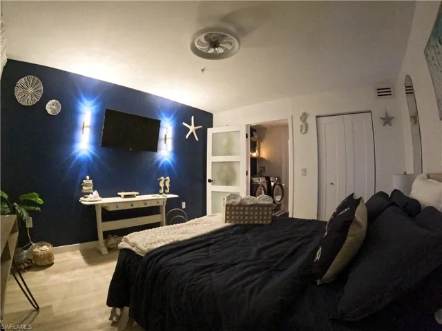 Bedroom featuring separate washer and dryer, wood finished floors, and an accent wall