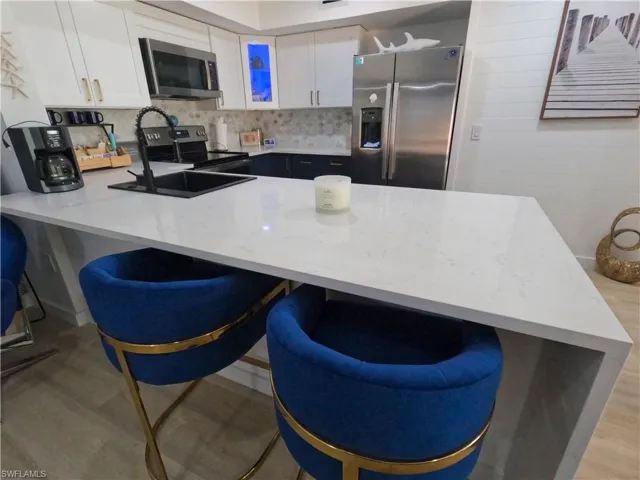 Kitchen with a kitchen bar, a peninsula, stainless steel appliances, and white cabinetry