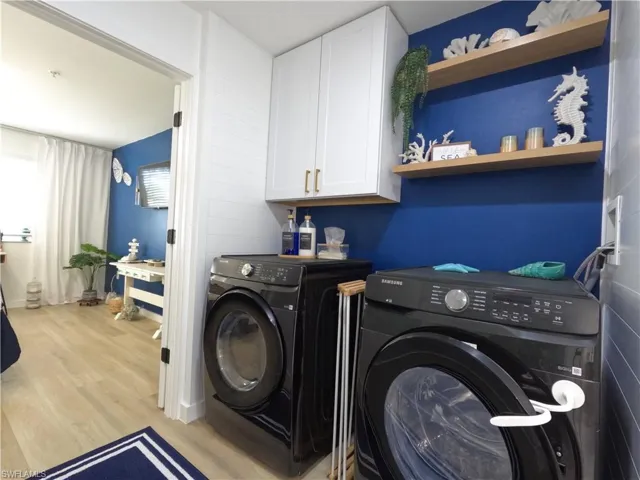 Laundry room featuring light wood-style floors, cabinet space, and separate washer and dryer