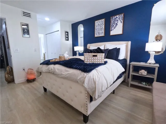 Bedroom with wood finished floors, arched walkways, and a closet