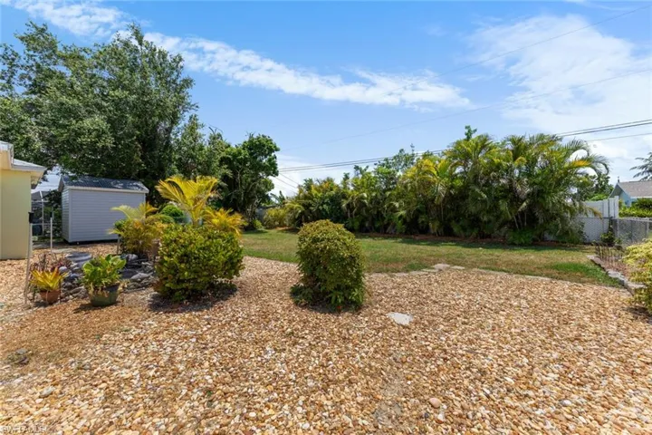 View of yard featuring a storage shed, fence, and an outdoor structure