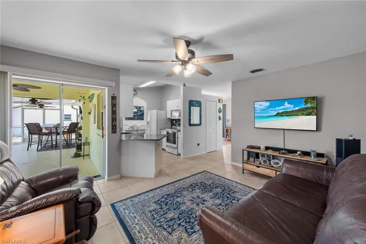 Living area featuring a ceiling fan, light tile patterned floors, and baseboards