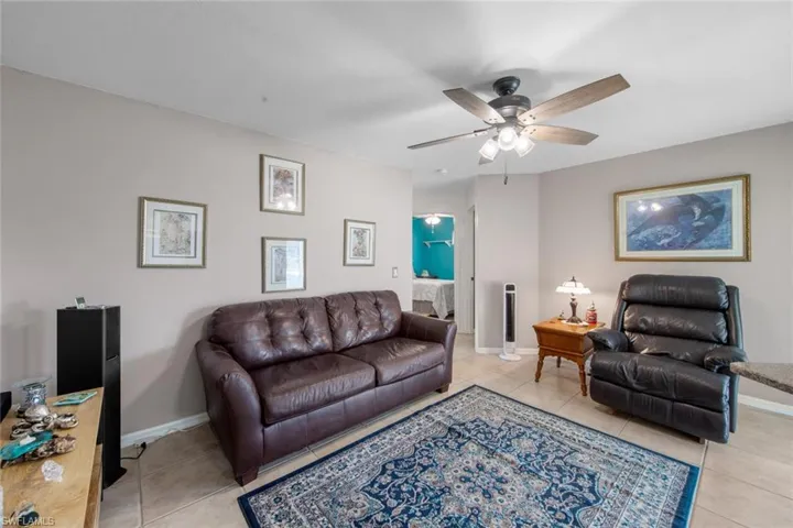 Living room featuring light tile patterned floors, ceiling fan, and baseboards