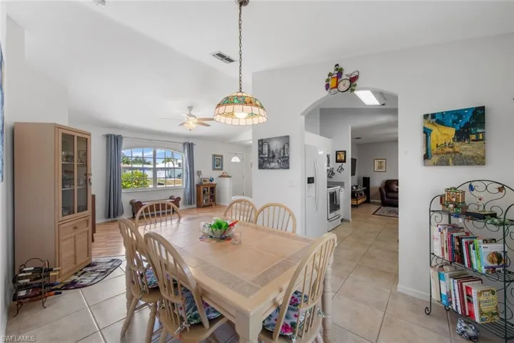 Dining space with arched walkways, light tile patterned flooring, and ceiling fan