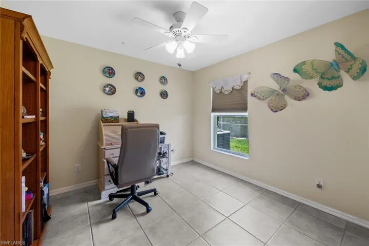 Home office featuring a ceiling fan, light tile patterned floors, and baseboards
