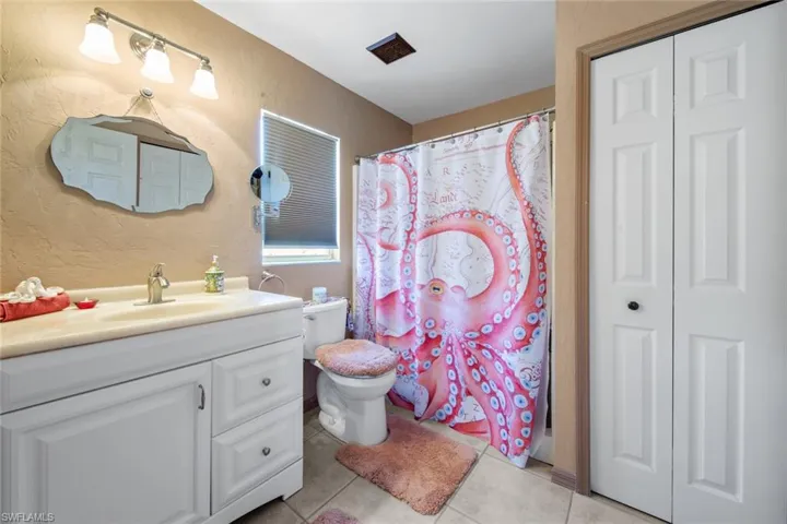 Bathroom with tile patterned flooring, vanity, toilet, a textured wall, and a shower with shower curtain
