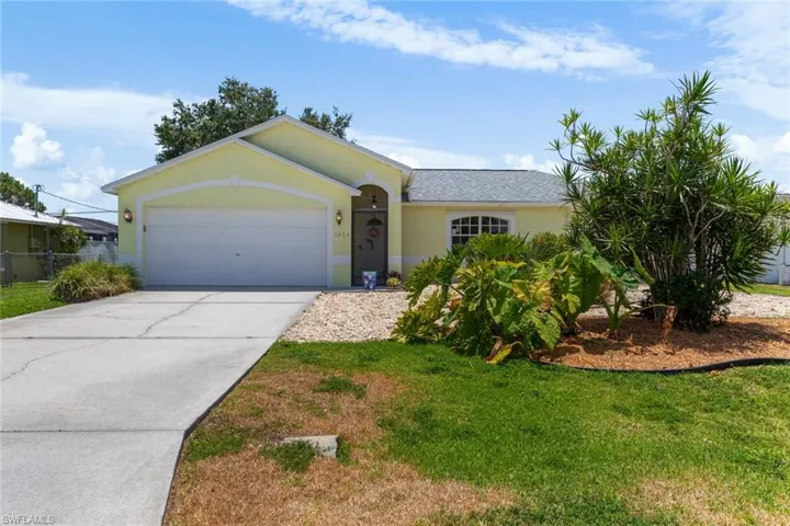 Ranch-style home featuring an attached garage, concrete driveway, stucco siding, and a front yard