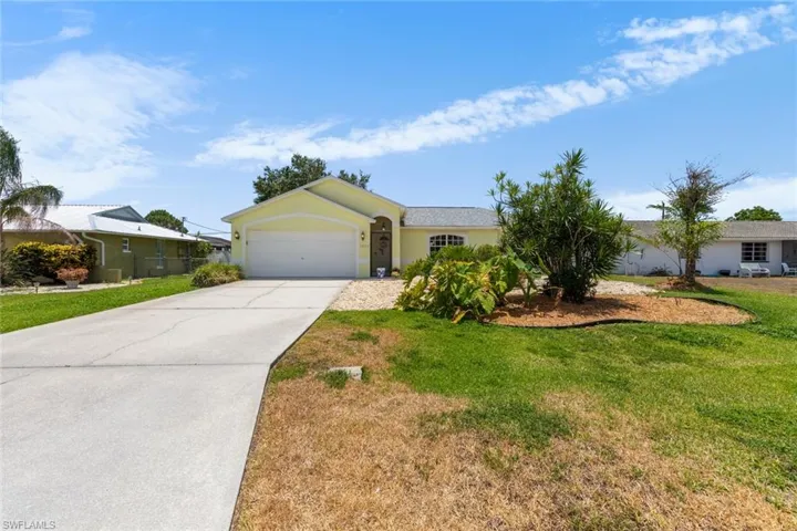 Ranch-style home with driveway, an attached garage, a front yard, and stucco siding