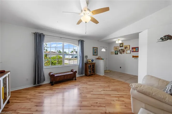 Living area with light wood-type flooring, a ceiling fan, vaulted ceiling, and baseboards