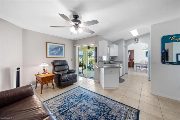 Living area with ceiling fan, arched walkways, light tile patterned flooring, and baseboards