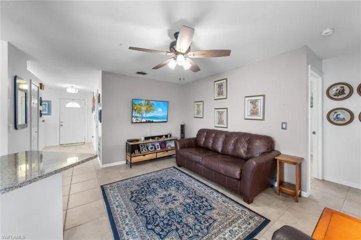 Living area featuring light tile patterned floors, a ceiling fan, and baseboards