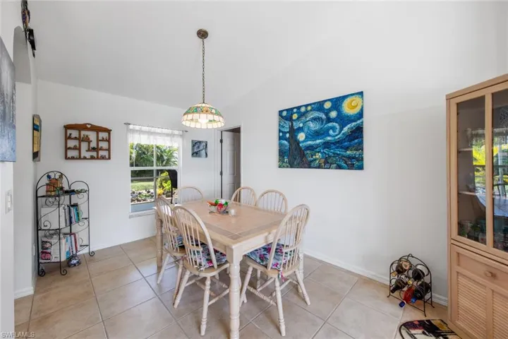 Dining space featuring light tile patterned floors, baseboards, and lofted ceiling