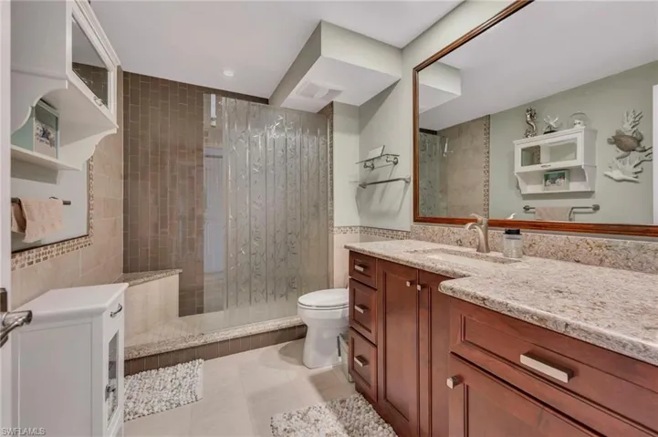 Bathroom featuring walk in shower, vanity, light tile patterned floors, and tile walls