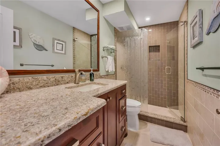 Bathroom with a shower stall, vanity, light tile patterned floors, and tile walls
