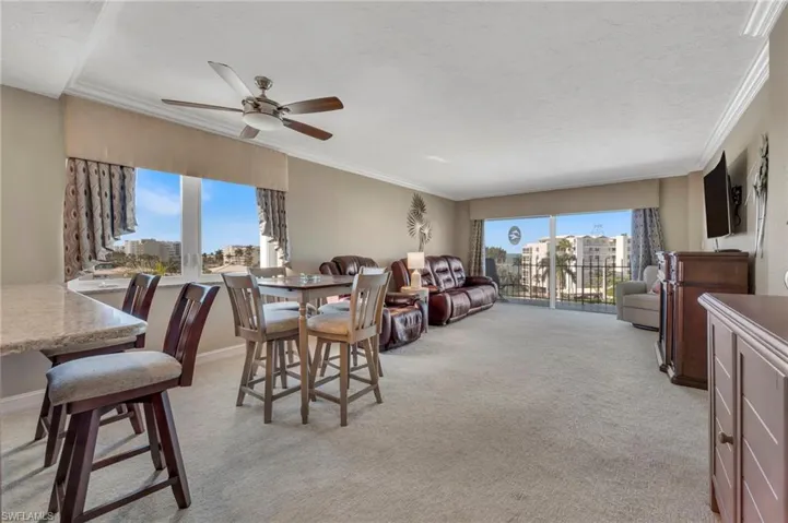 Dining space featuring a ceiling fan, light carpet, ornamental molding, and a textured ceiling