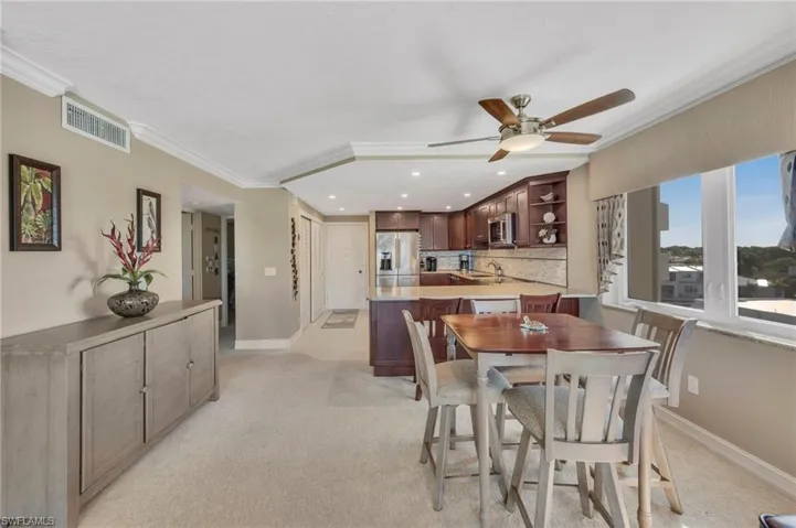 Dining area with ornamental molding, light colored carpet, a ceiling fan, and recessed lighting