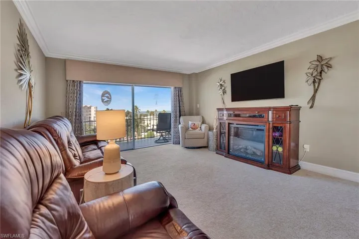 Living area with a glass covered fireplace, carpet floors, and ornamental molding
