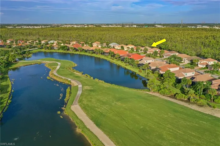 Aerial view of property and surrounding area featuring nearby suburban area, a large body of water, and a golf course