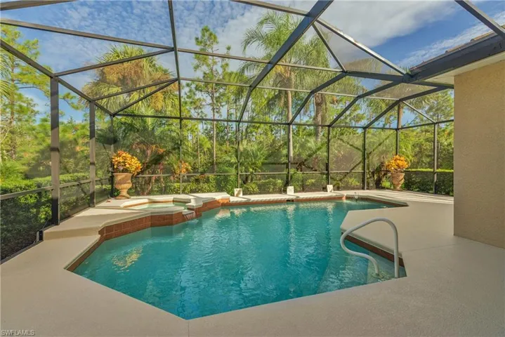 View of swimming pool with a sunroom, glass enclosure, a pool with connected hot tub, and a patio