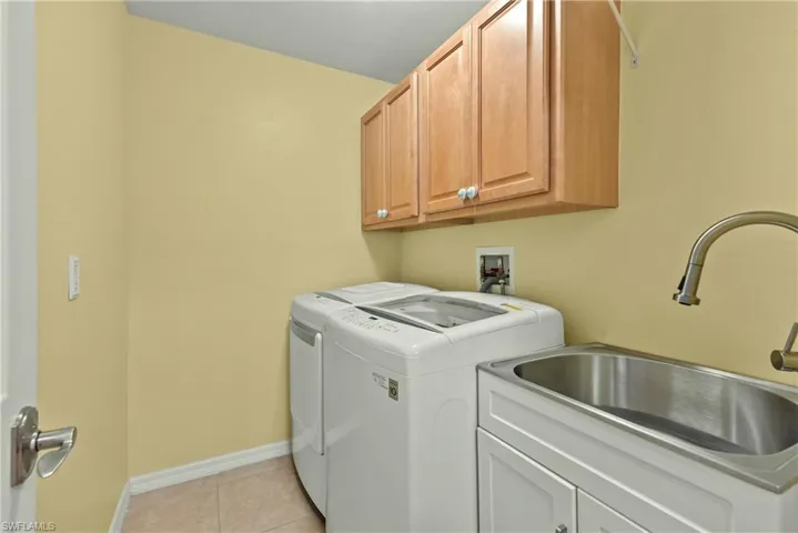 Laundry area featuring cabinet space, light tile patterned floors, and washer and dryer