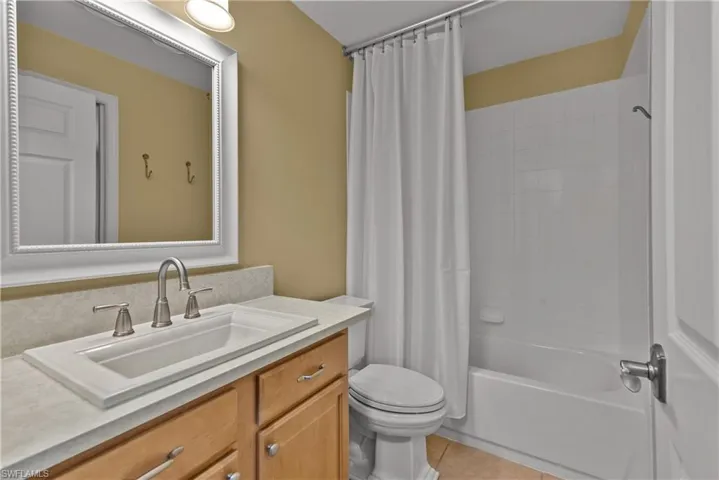 Bathroom #2 featuring shower / bathtub combination with curtain, vanity, and light tile patterned flooring