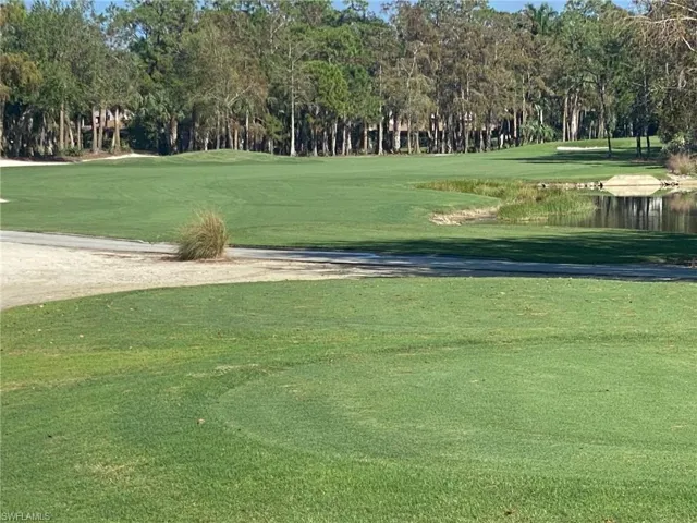 View of property's community featuring view of golf course, view of wooded area, and a yard