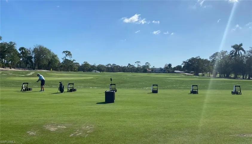 View of property's community with view of golf course, view of scattered trees, and a lawn