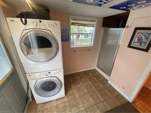 Laundry room featuring brick patterned floors and stacked washing machine and dryer