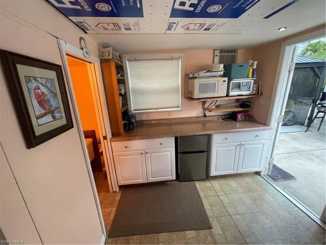 Kitchen featuring fridge, white cabinetry, and light stone countertops