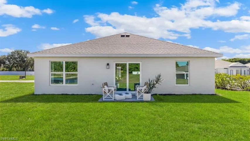 Model home. Rear view of property with roof with shingles, a yard, stucco siding, and a patio