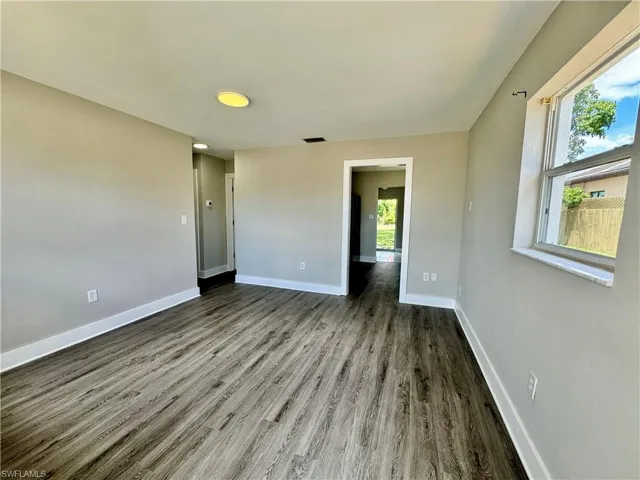 Unfurnished bedroom with baseboards and dark wood-style flooring