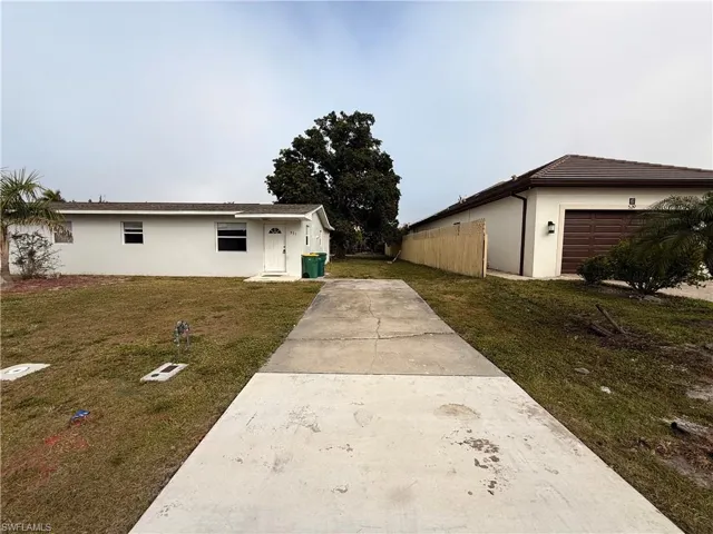 Ranch-style home with stucco siding, a front lawn, and concrete driveway