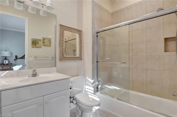 Guest bathroom featuring combined bath / shower with glass door, vanity, and toilet