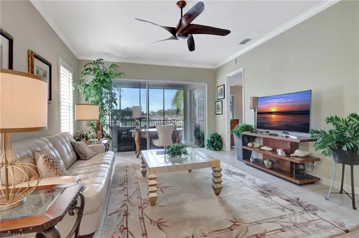 Tiled living room featuring ceiling fan and ornamental molding