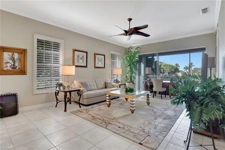Tiled living room with ceiling fan and crown molding