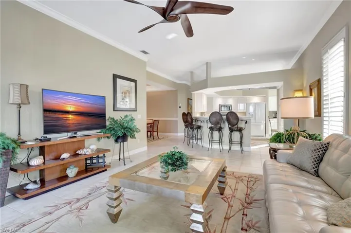 Tiled living room with ceiling fan and ornamental molding